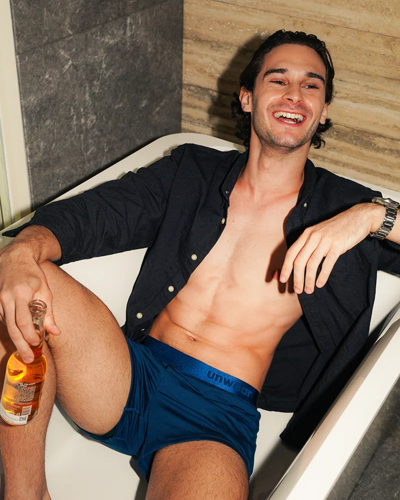 model wearing unwear boxer shorts lounging in an empty bathtub